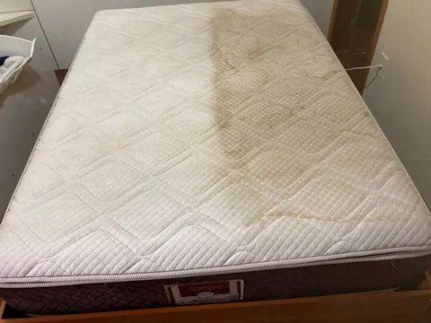 Colchão claro com manchas amarronzadas antes da avaliação de limpeza