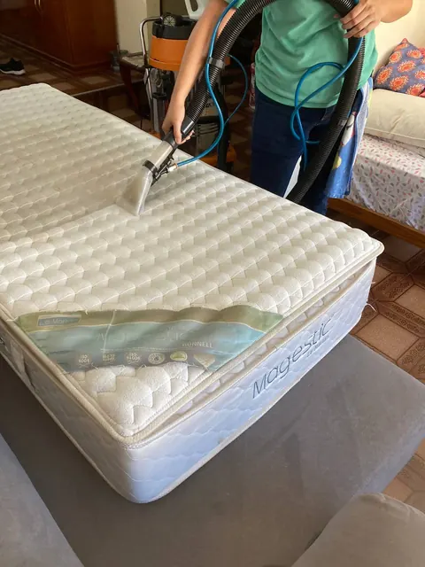 Profissional realizando limpeza por extração em colchão claro