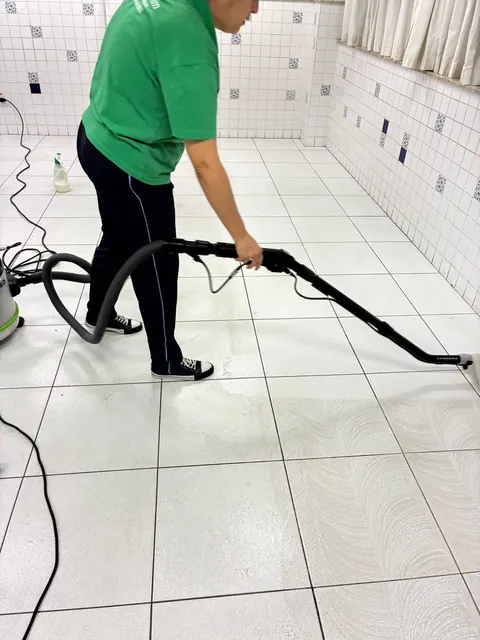 Profissional realizando limpeza técnica em piso cerâmico com equipamento de extração